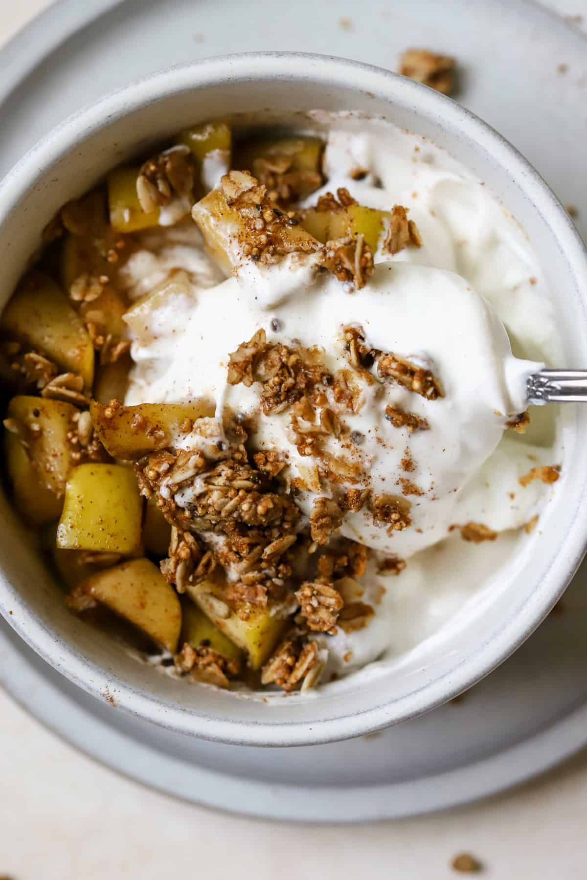 Spoon digging into apple pie yogurt bowl.