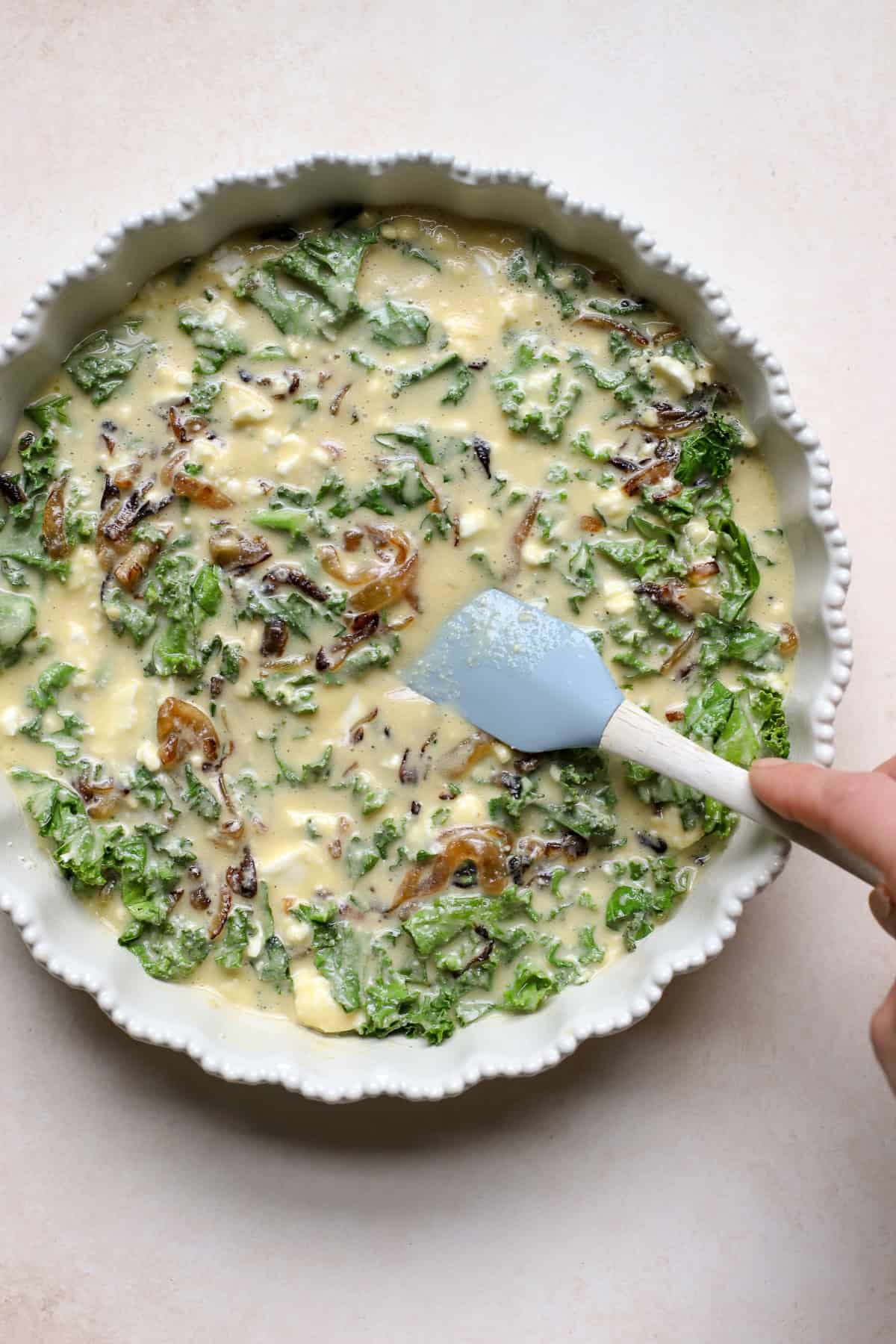 Kale pie ingredients combined in ceramic pie dish just before baking.