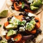 Vegetarian black bean tacos with carrots and lime on serving board.
