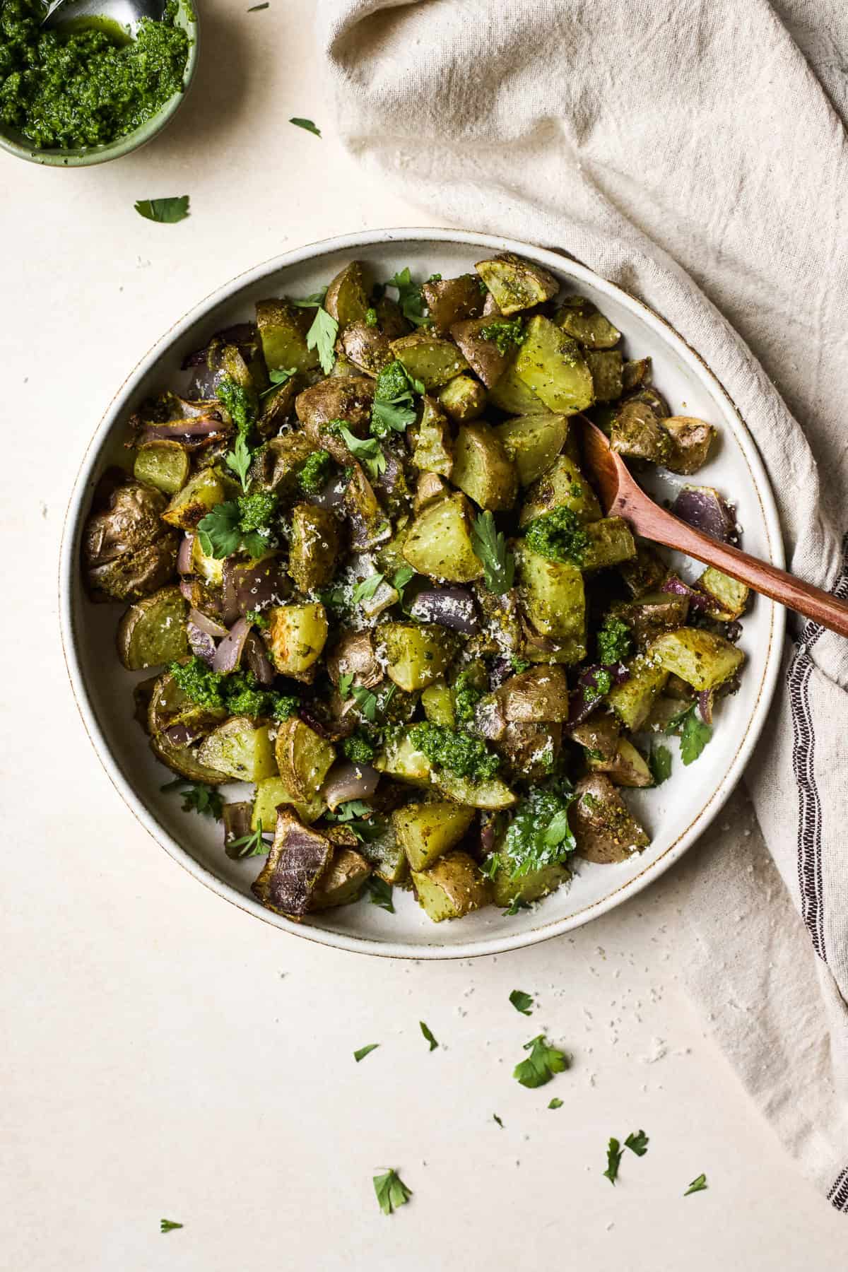 Pesto roasted potatoes in white bowl with spoon.