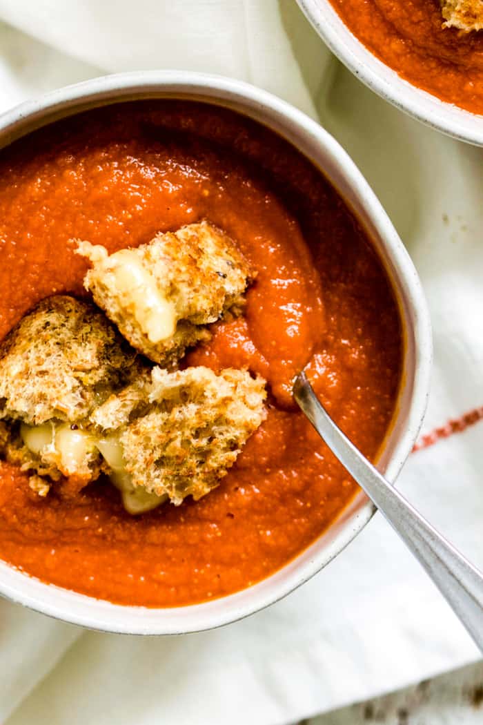 Bowl of spicy tomato and red lentil soup topped with grilled cheese croutons.