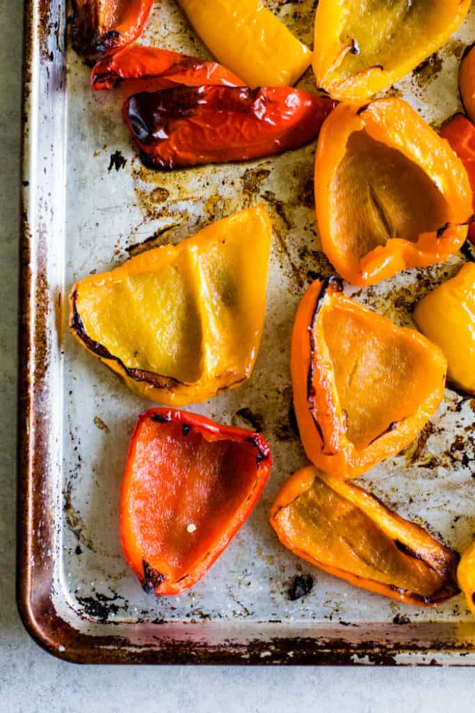 Fully roasted bell peppers on sheet pan.
