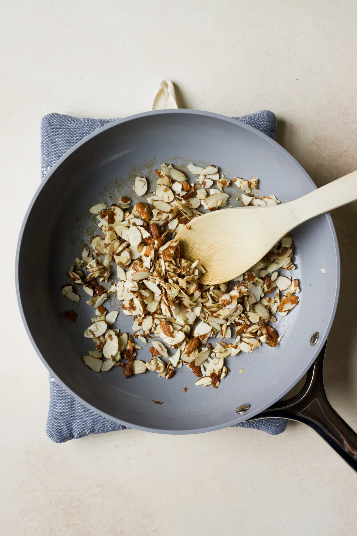 Adding sliced almonds to the pan to sauté.