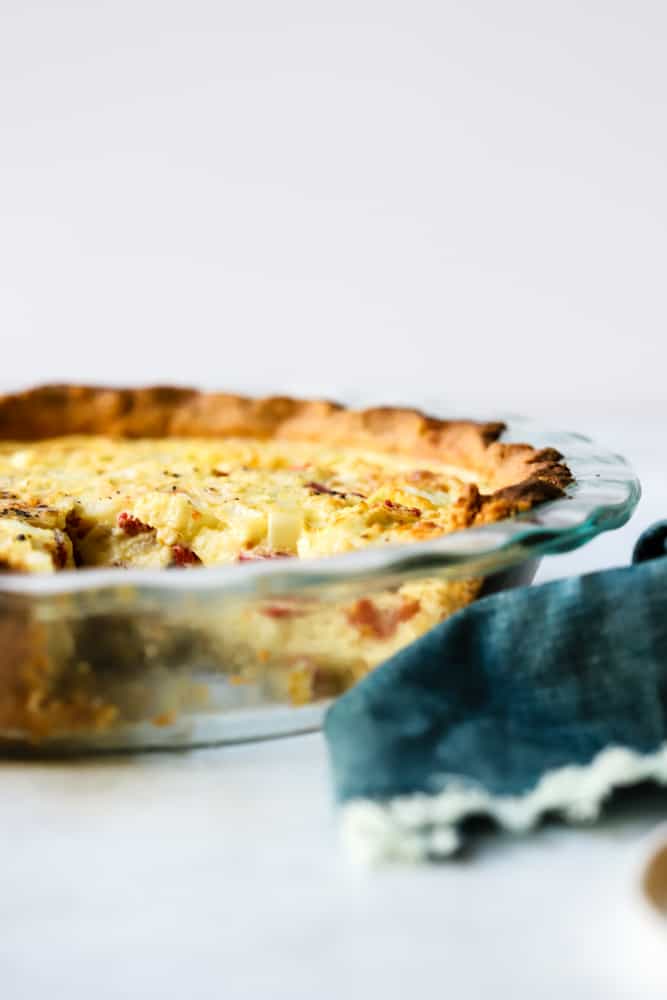 Simple quiche with chickpea flour baked in clear glass pie dish with slice taken out