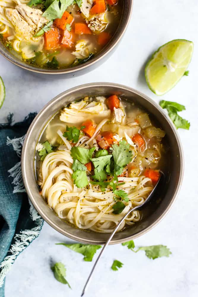 Ginger lime chicken noodle soup in a bowl with a spoon.
