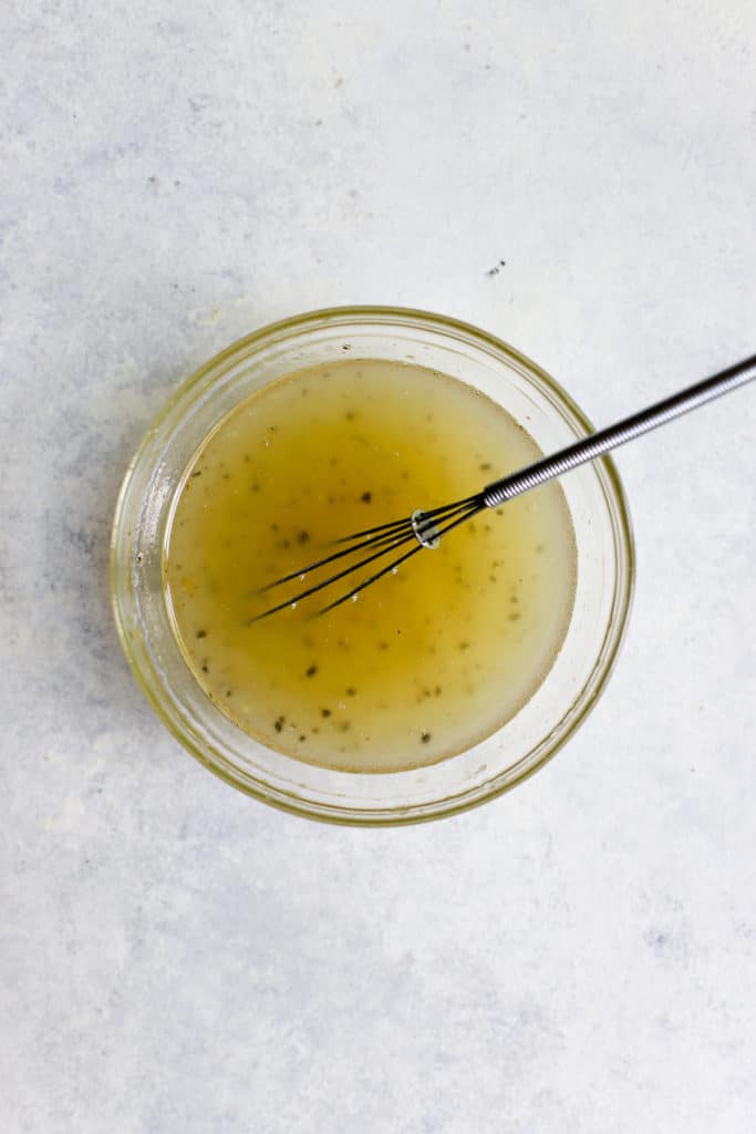 Tangy vinegar dressing for cucumber salad in a bowl with mini whisk.
