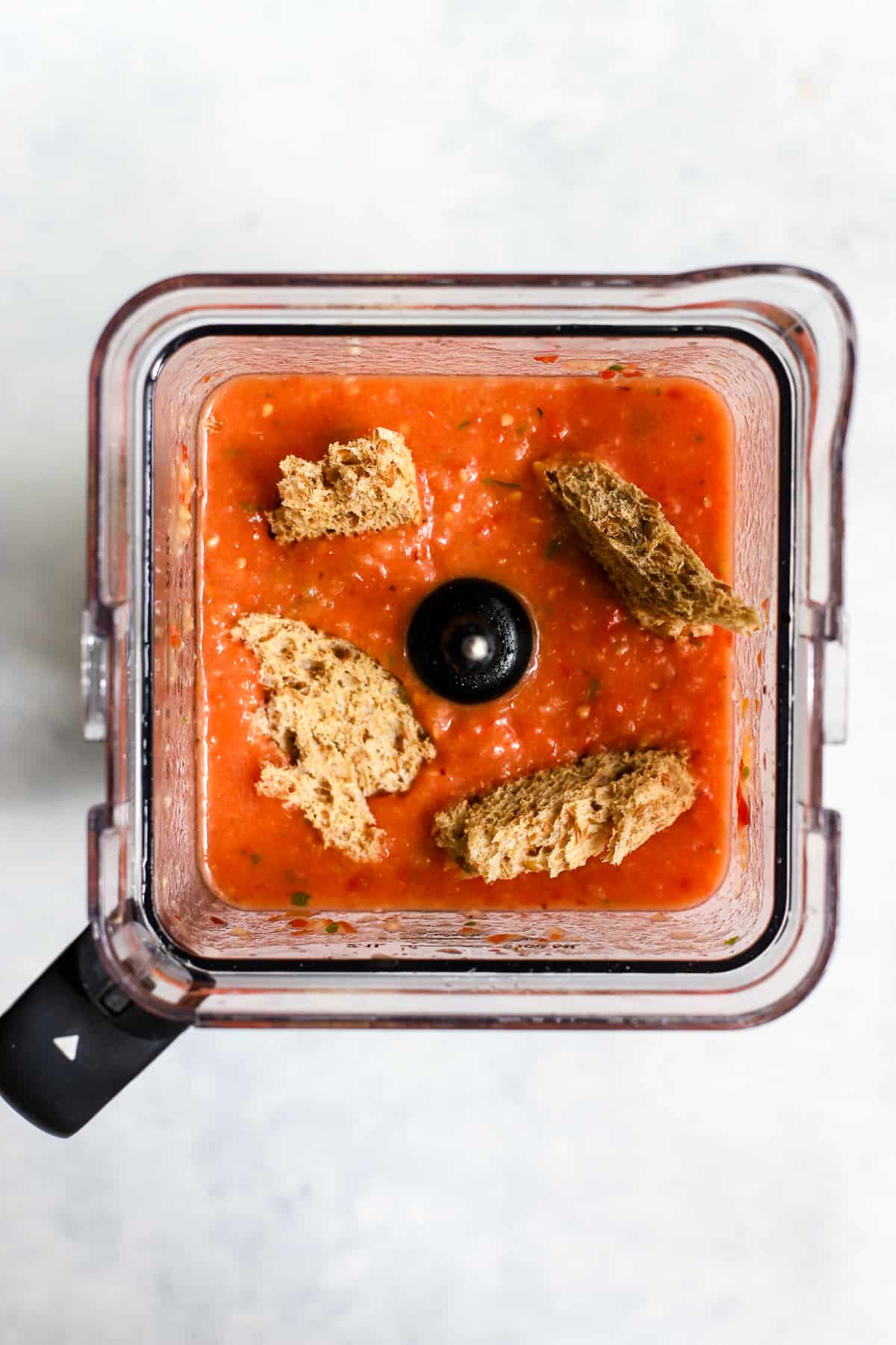 Day-old bread pieces soaking into gazpacho in blender.