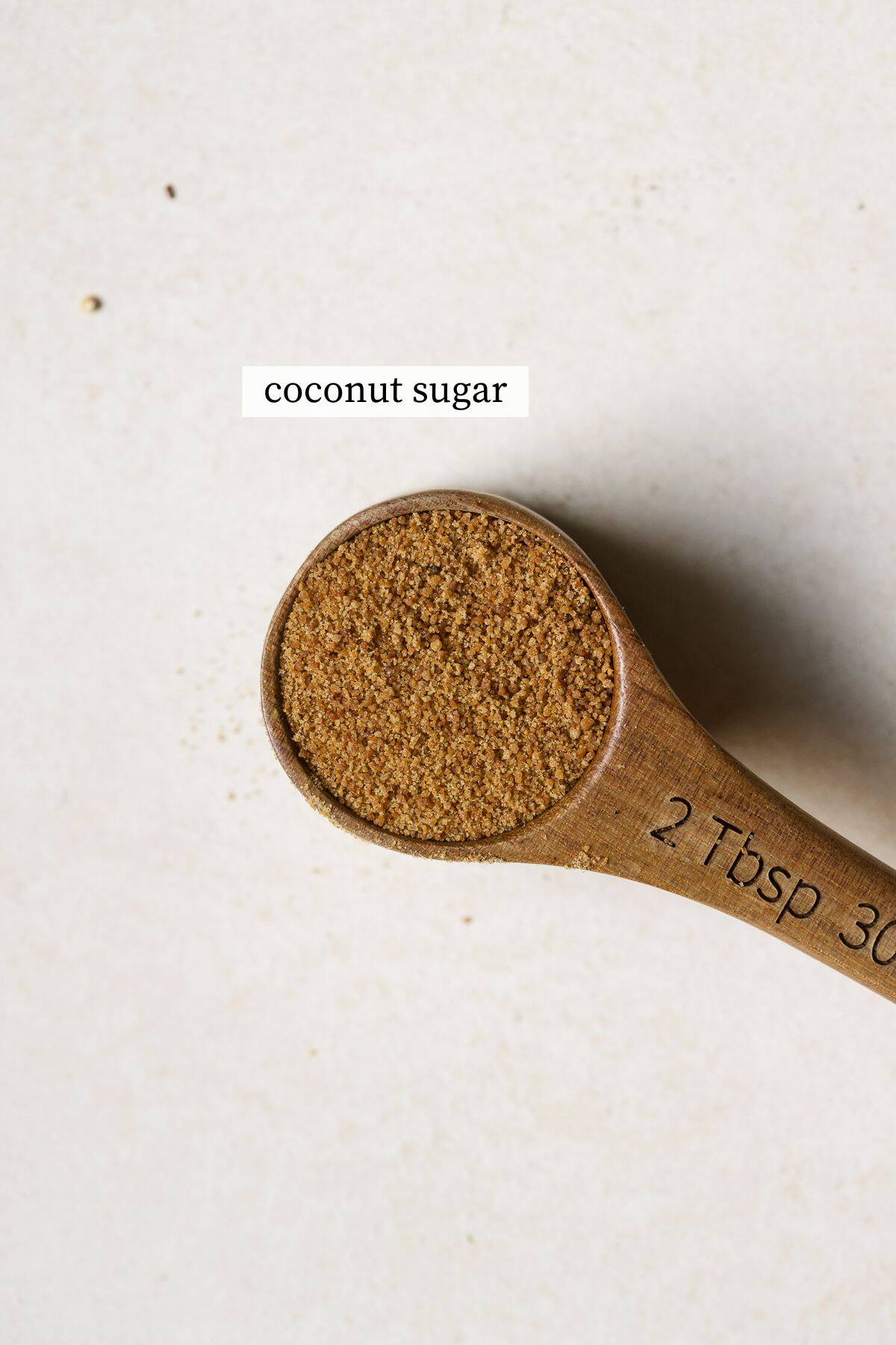 Coconut sugar in wooden tablespoon measure.