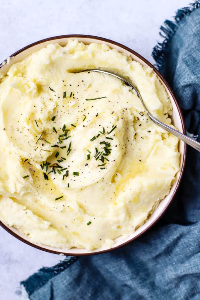 Healthy pressure cooker mashed potatoes in a bowl with butter and chives on top.