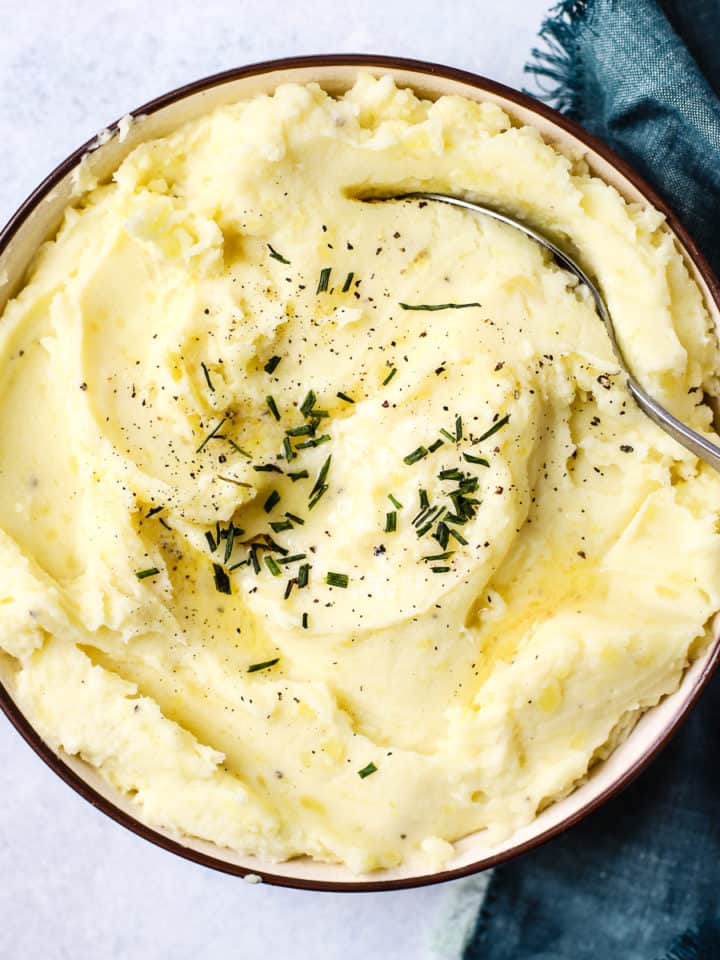 Healthy pressure cooker mashed potatoes in a bowl with butter and chives on top.