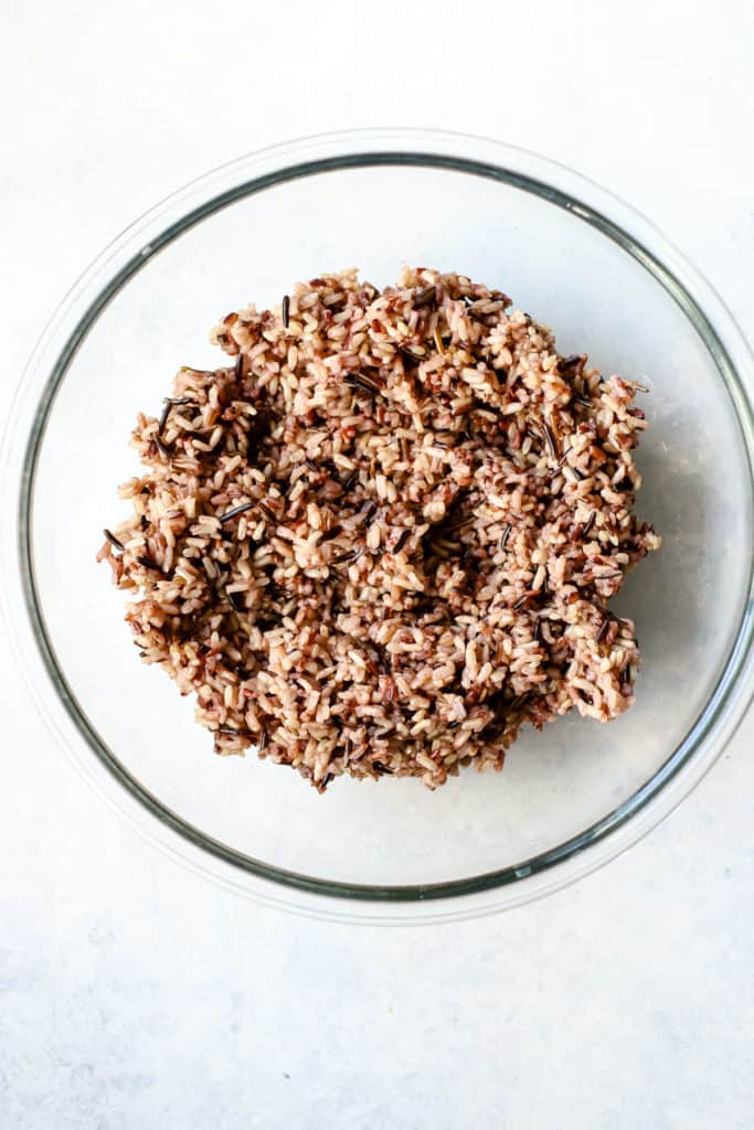 Cooked wild rice blend cooling in a large bowl, before adding other salad ingredients.