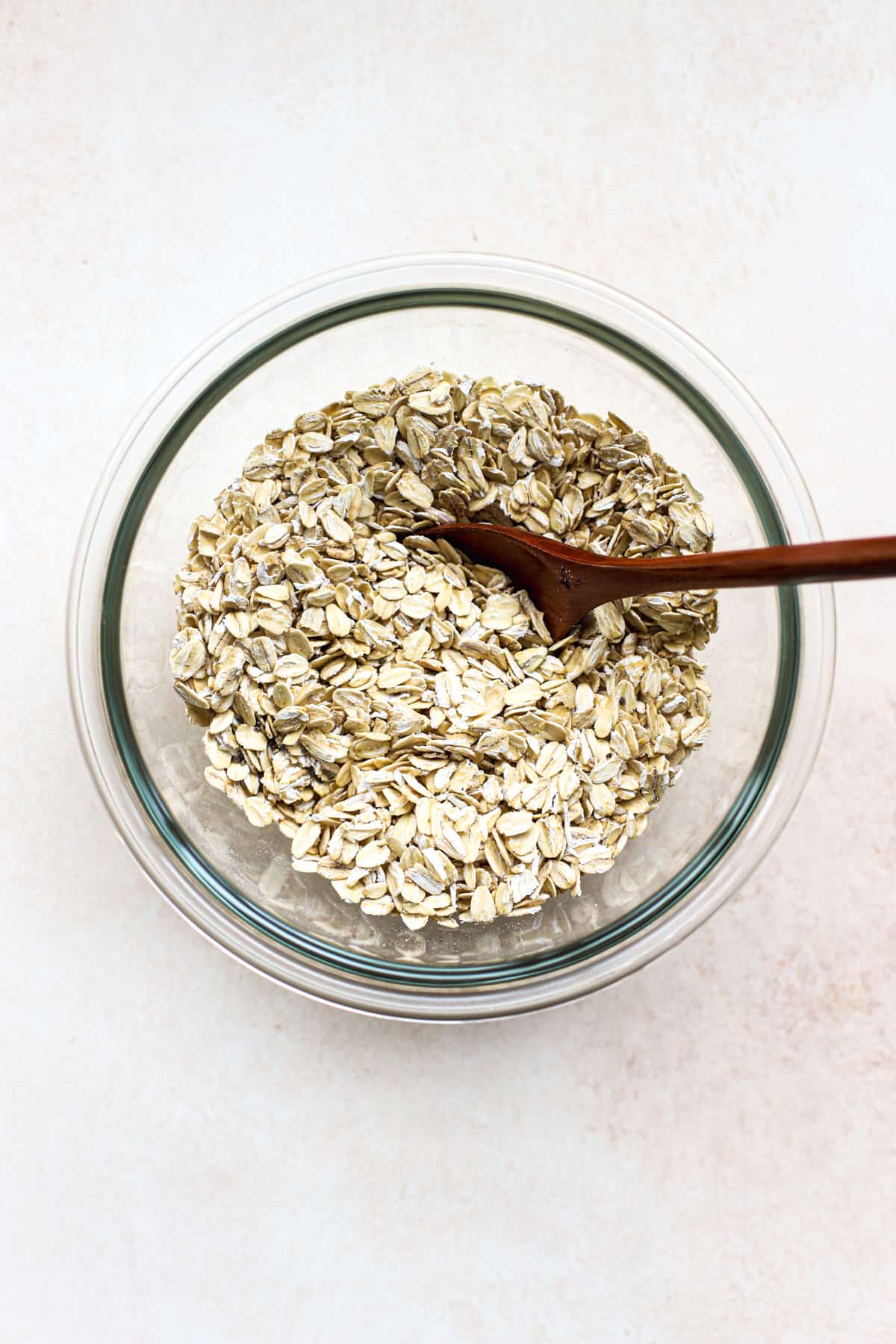 Oats, chia seeds, and salt mixed together in bowl with wooden spoon.