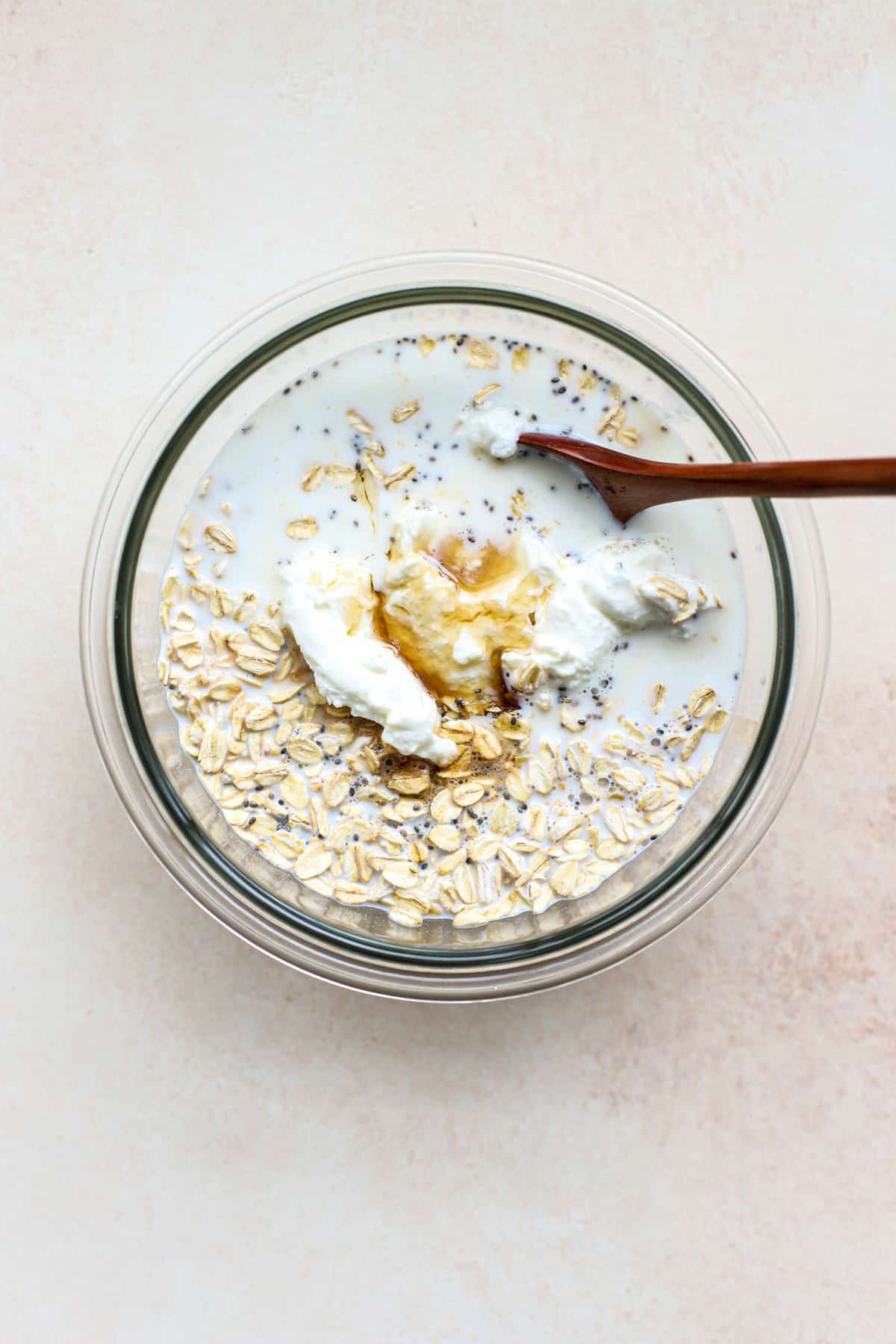 All protein overnight oats ingredients combined in a bowl before being fully stirred together.