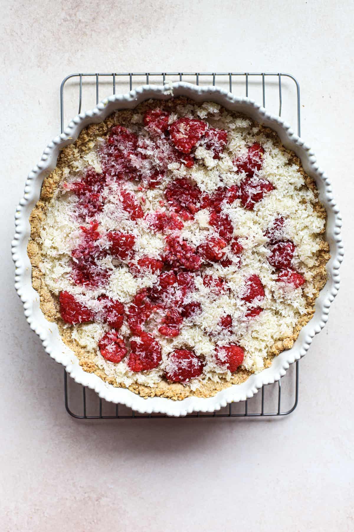 Coconut macaroon filling mixture spread in with raspberries in macaroon crust