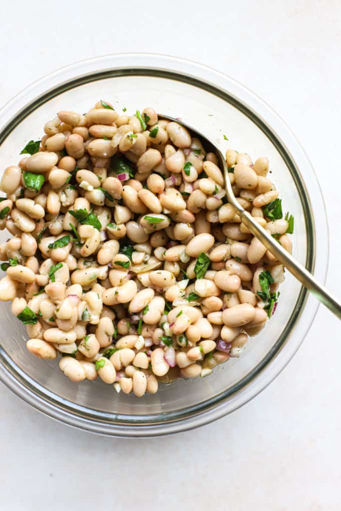 Marinated white beans in a glass bowl.
