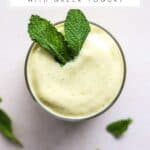 Smoothie with mango and mint in a glass with fresh mint garnish.