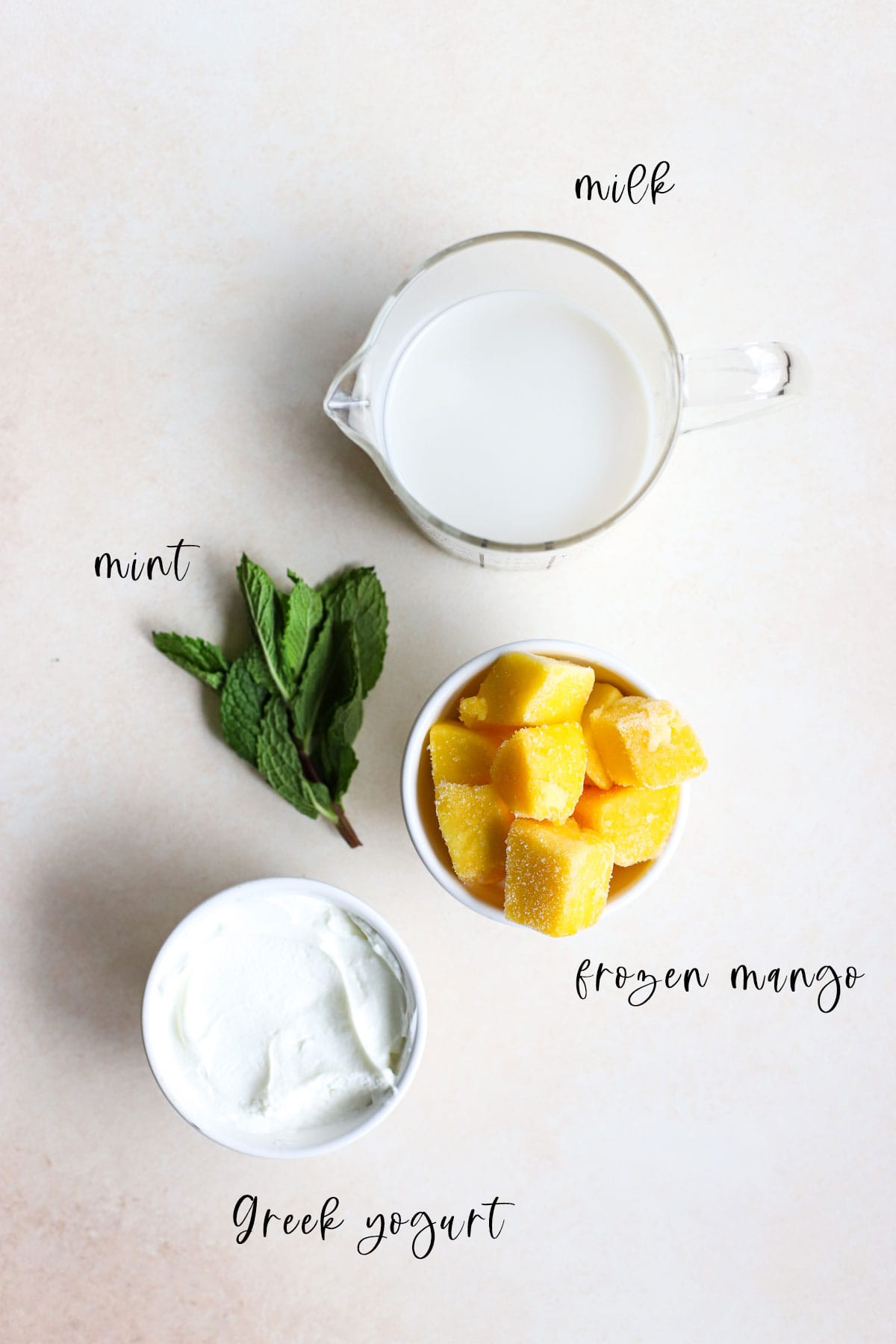 Frozen mango, Greek yogurt, fresh mint, and milk for making smoothies.