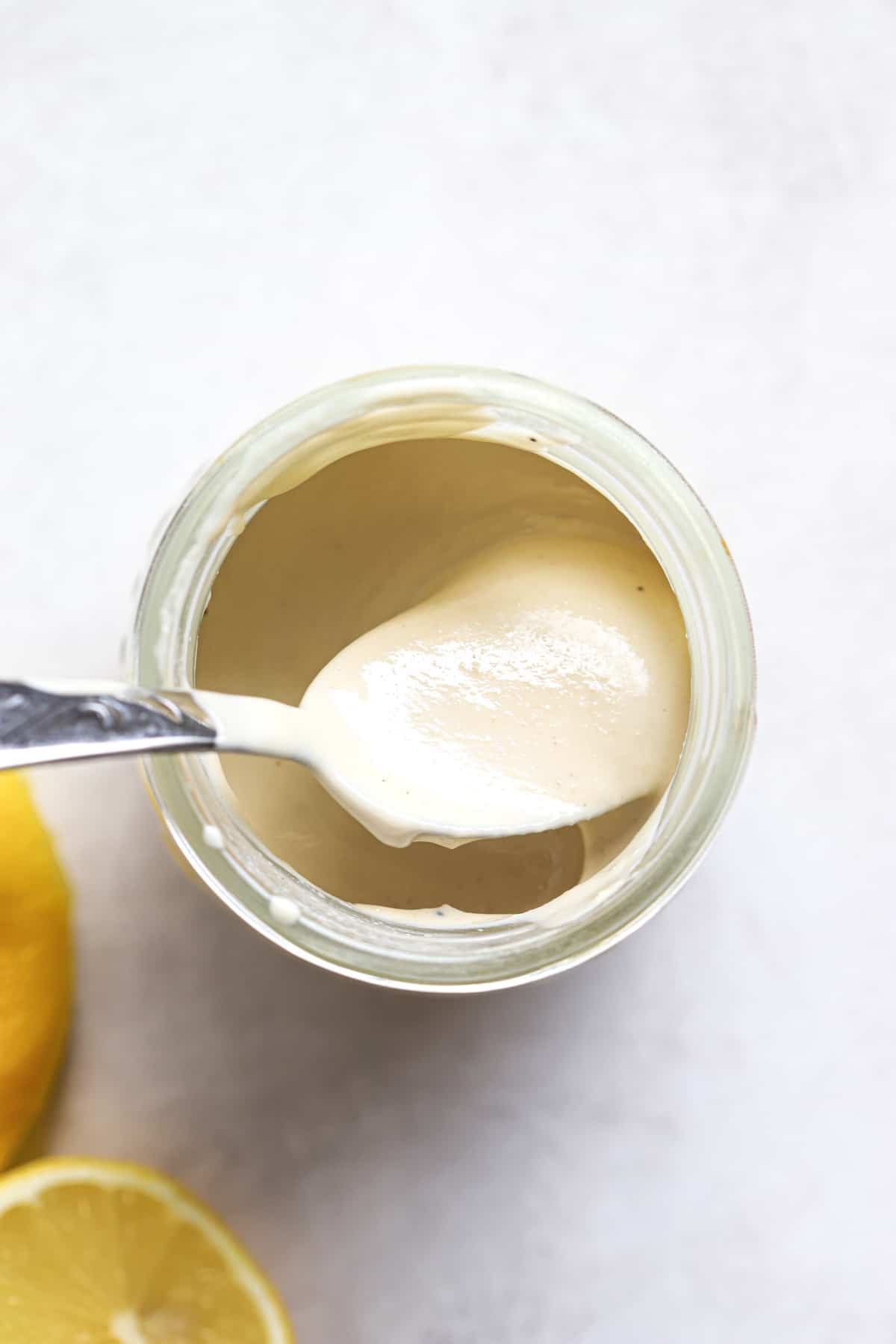 Lemon tahini sauce in a small jar with spoon.