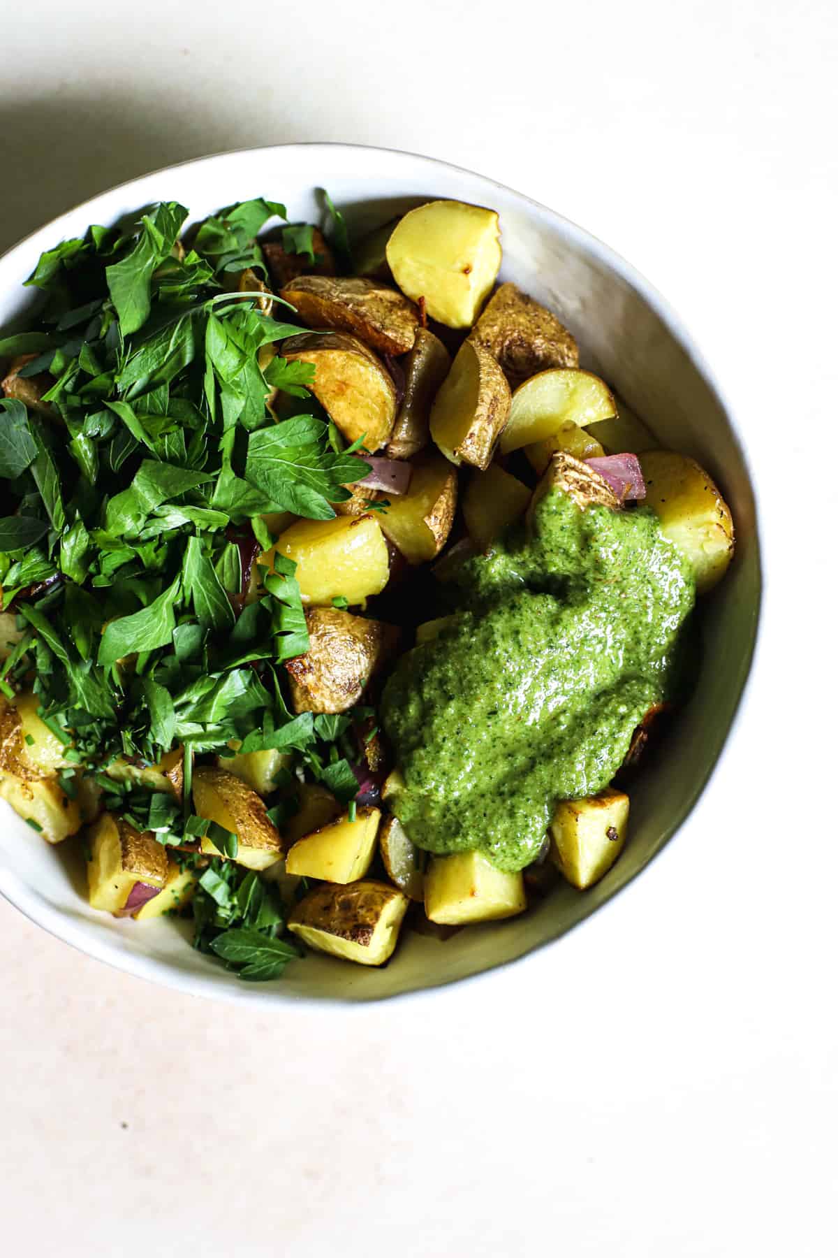 Pesto potato salad ingredients in white ceramic bowl