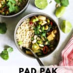 Two gray bowls with pad pak, served with brown rice, with limes wedges and cilantro on the side