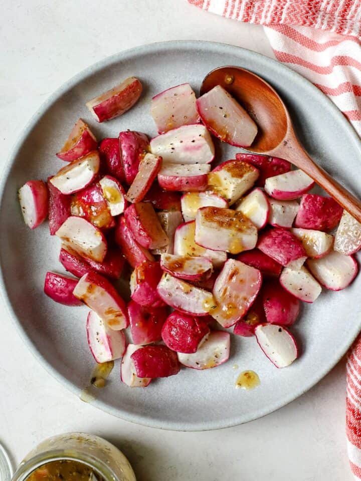 Roasted radishes tossed with vinaigrette in blue bowl.