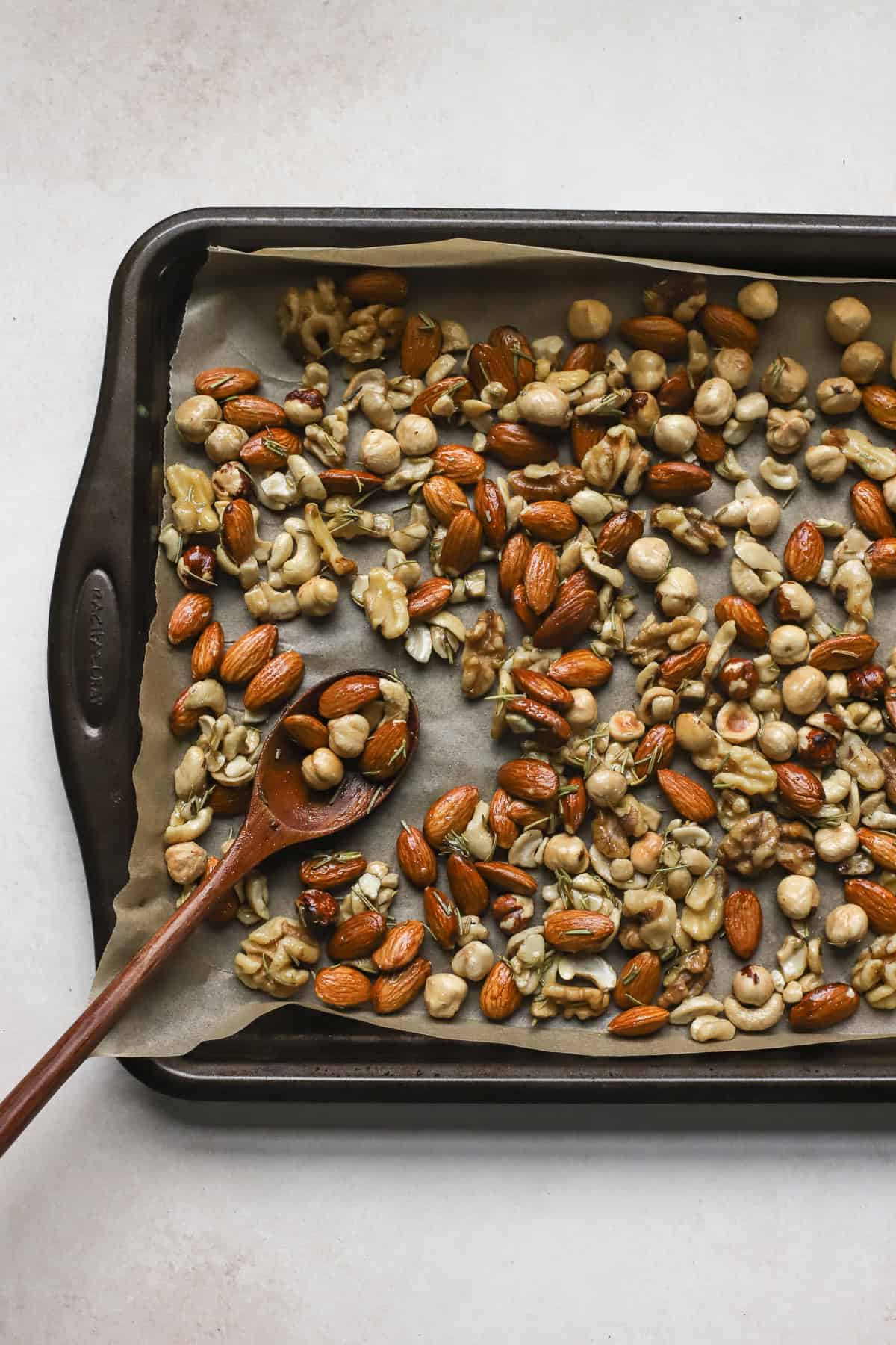 Seasoned rosemary nuts on rimmed sheet pan before baking.