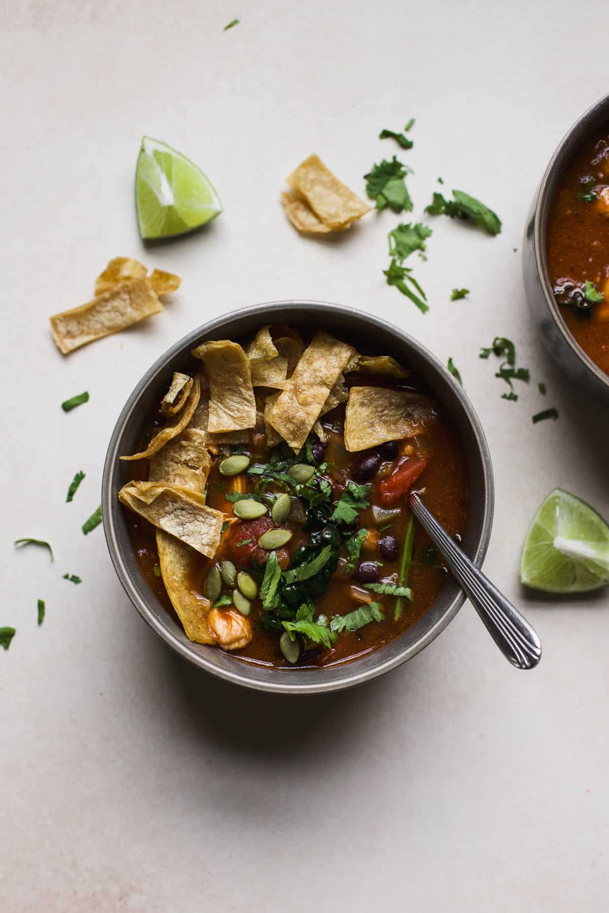 Chicken tortilla soup in gray bowl with spoon.