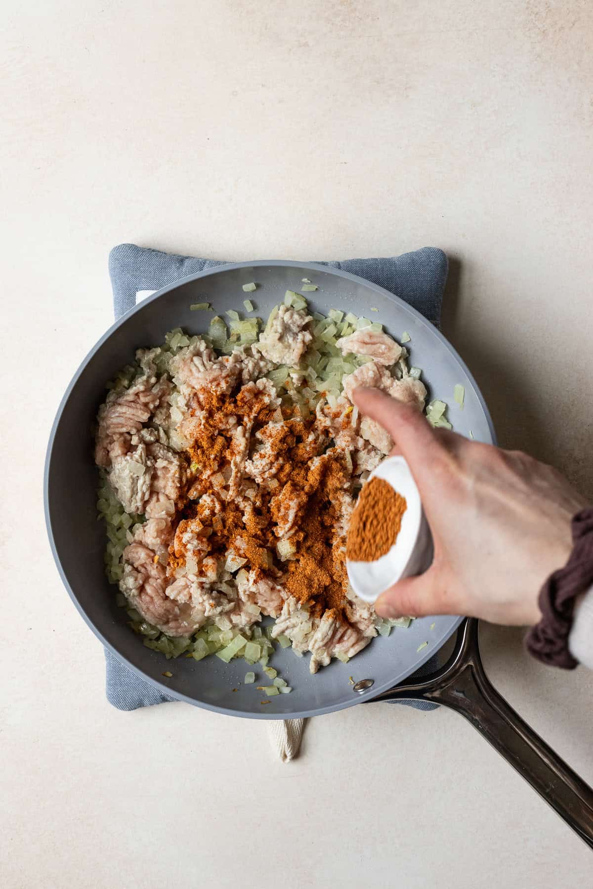 Seasoning ground chicken with taco spices.