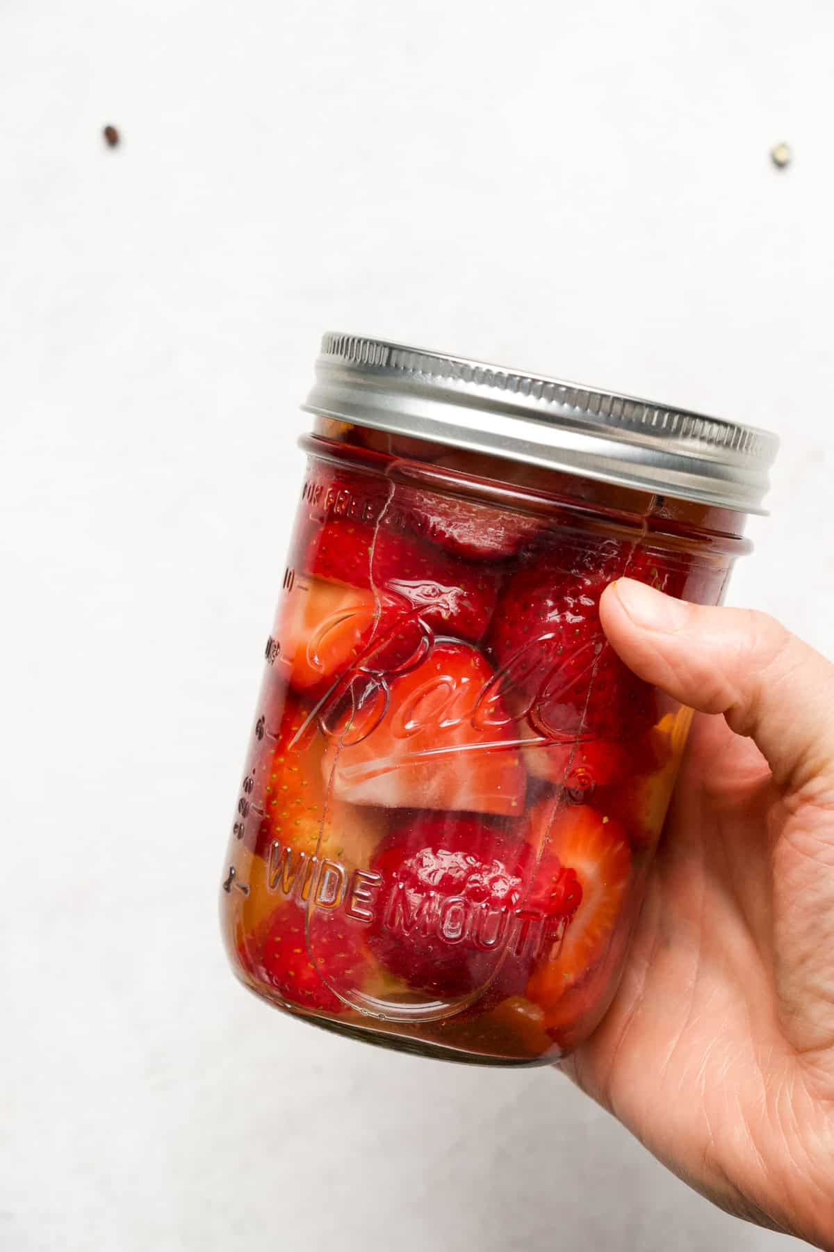 Holding a jar of quick pickled strawberries.