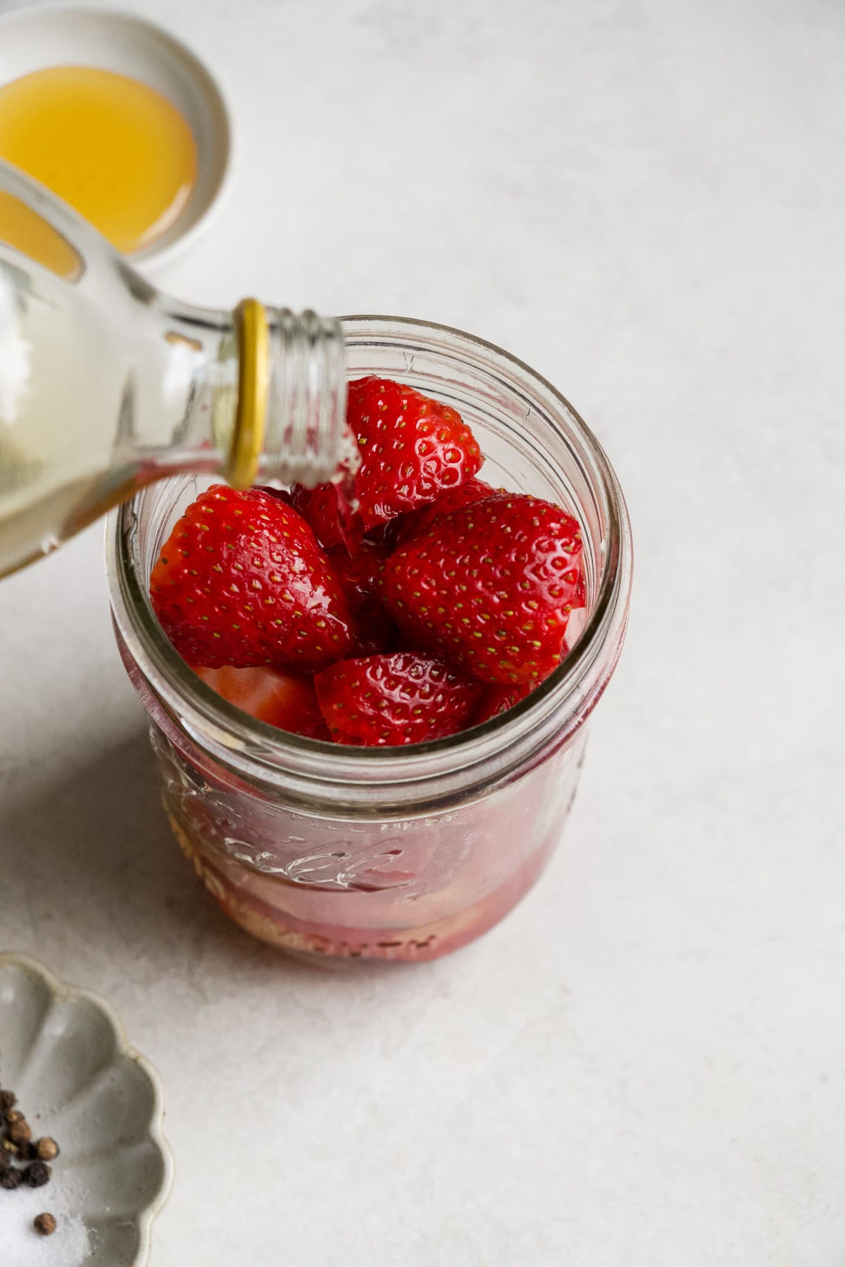 Pouring vinegar into jar of strawberries.