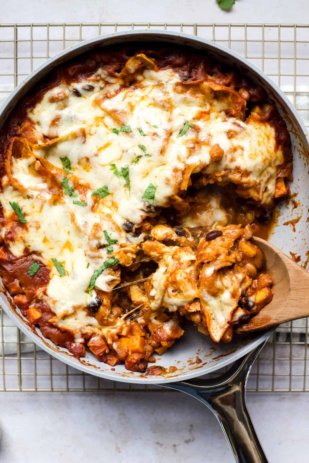 Vegetarian black bean and sweet potato skillet enchiladas being scooped out of pan.