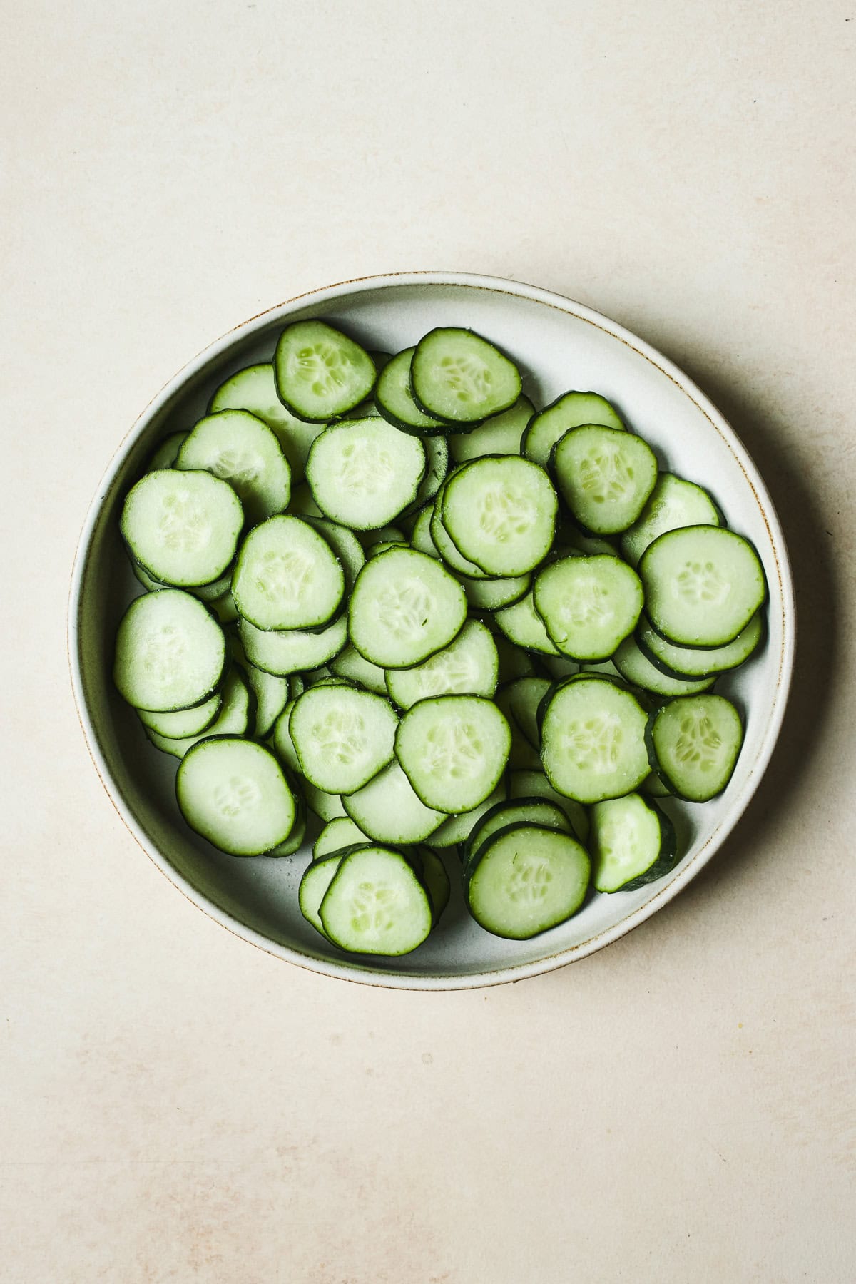 Sliced and salted cucumbers in a bowl.