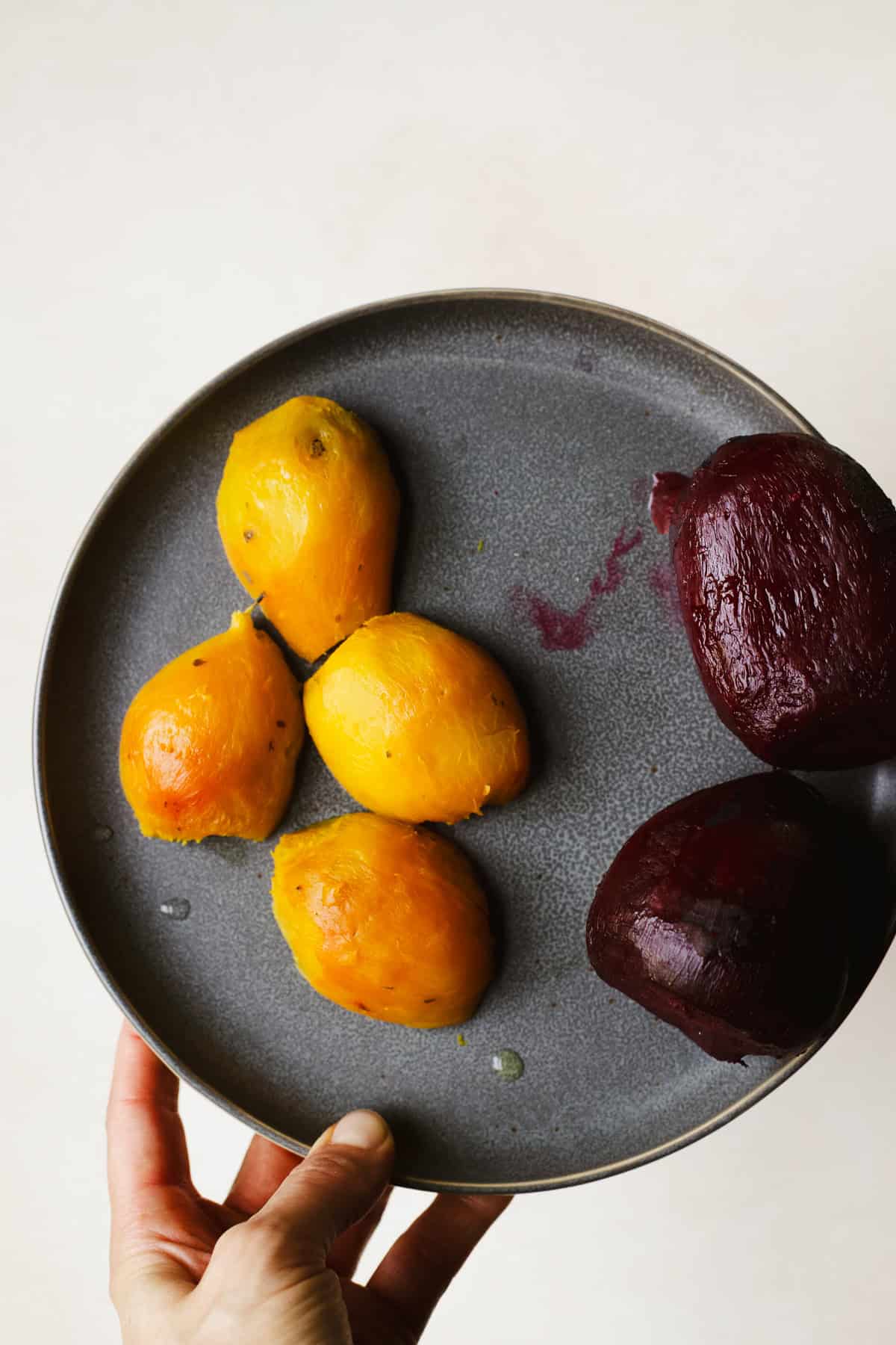 Fully peeled roasted golden beets and roasted red beets on a plate.