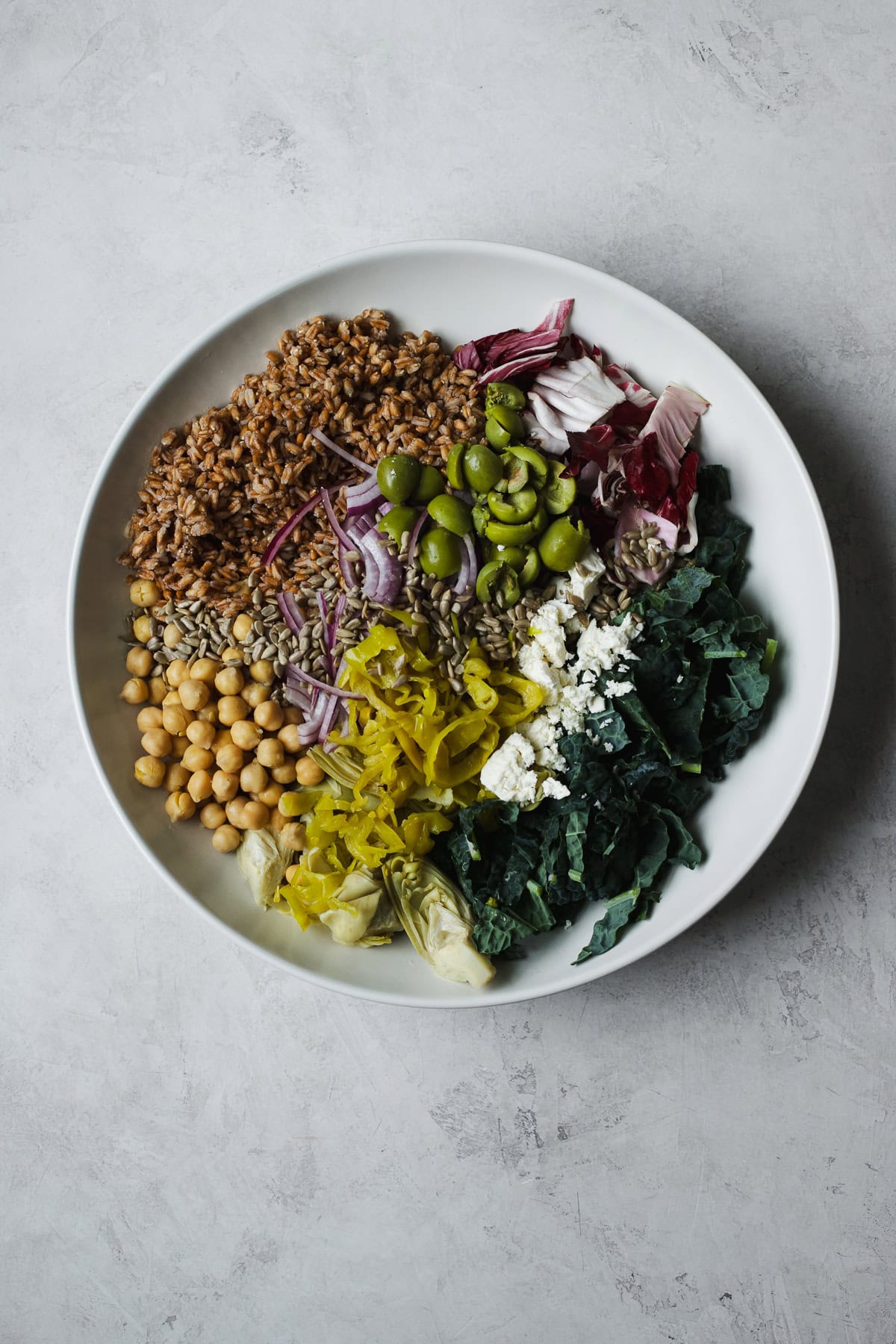 Farro and kale salad ingredients in a large serving bowl before being tossed.