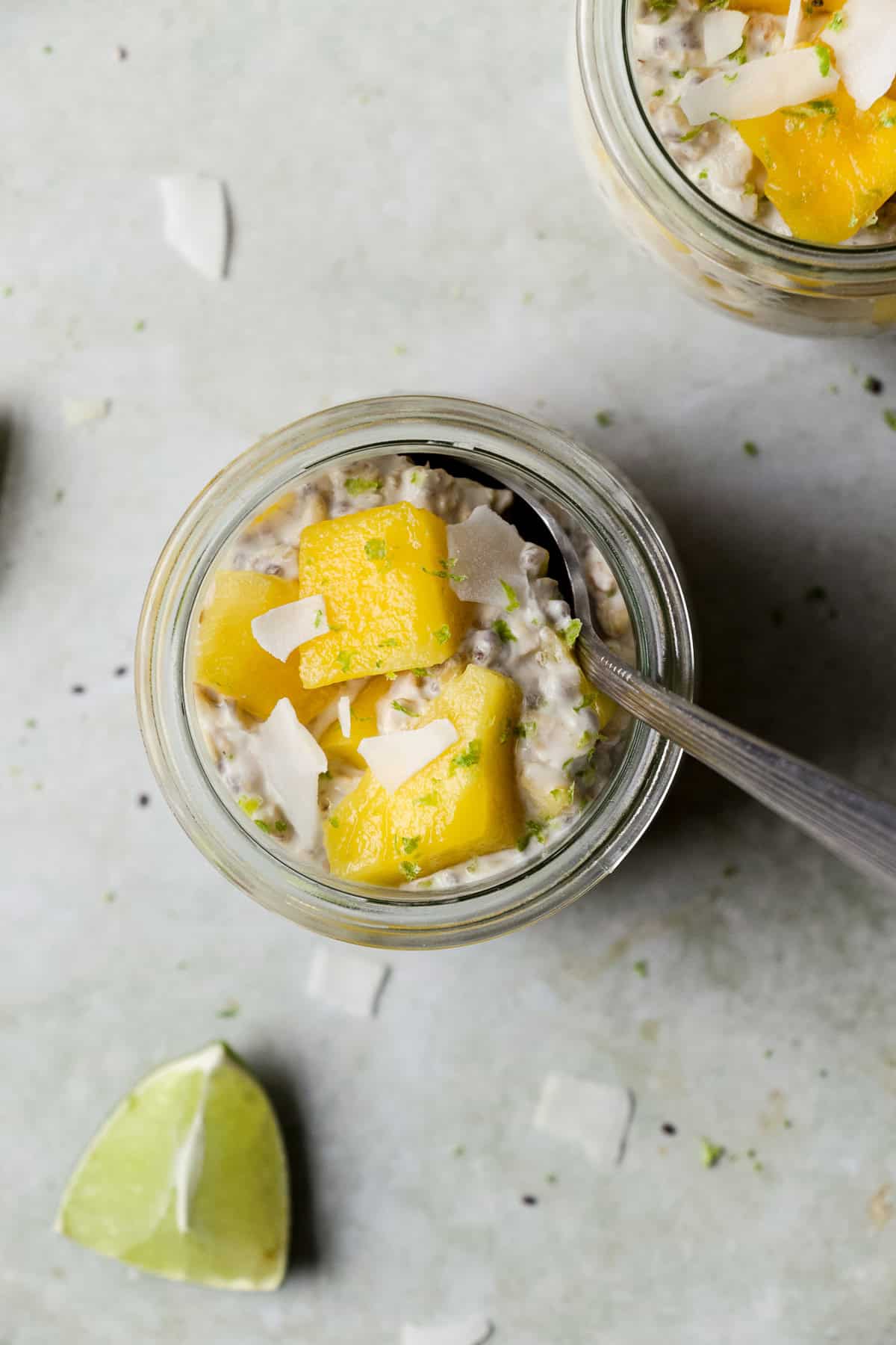 Mango lime overnight oats in a small jar with a spoon.