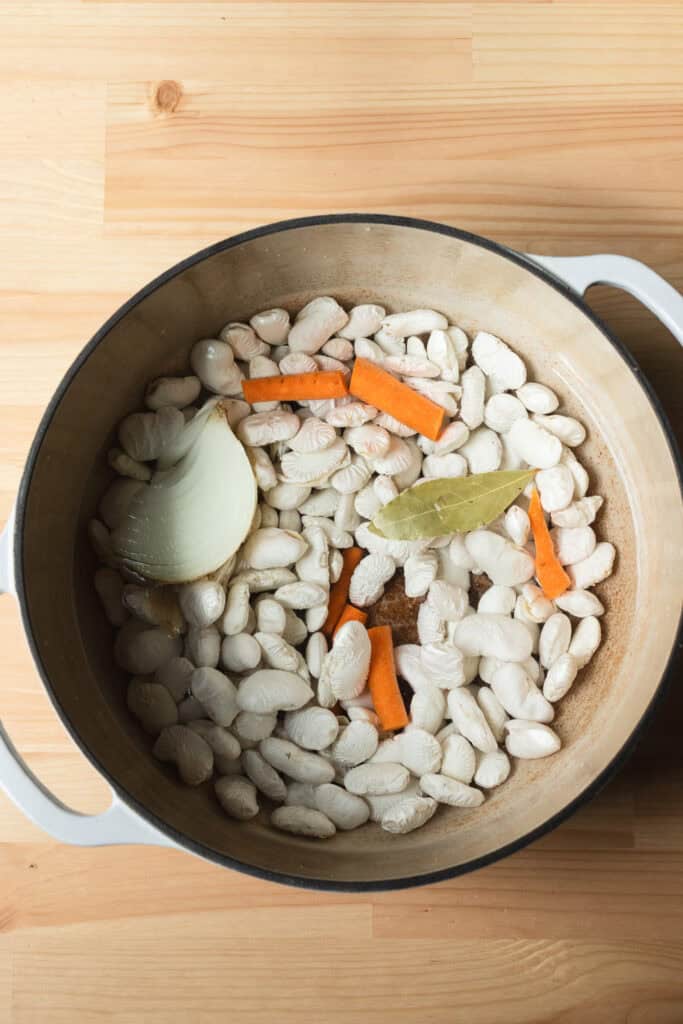Royal Corona beans in a dutch oven with aromatics.