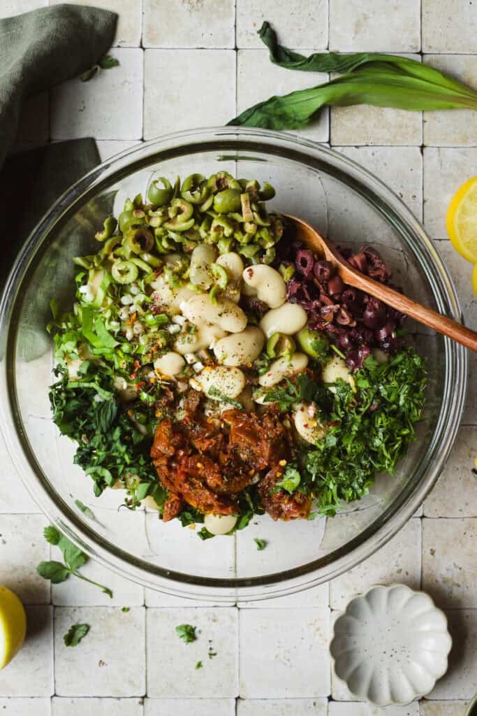 Royal Corona white beans and other briny, herby ingredients in a large bowl.