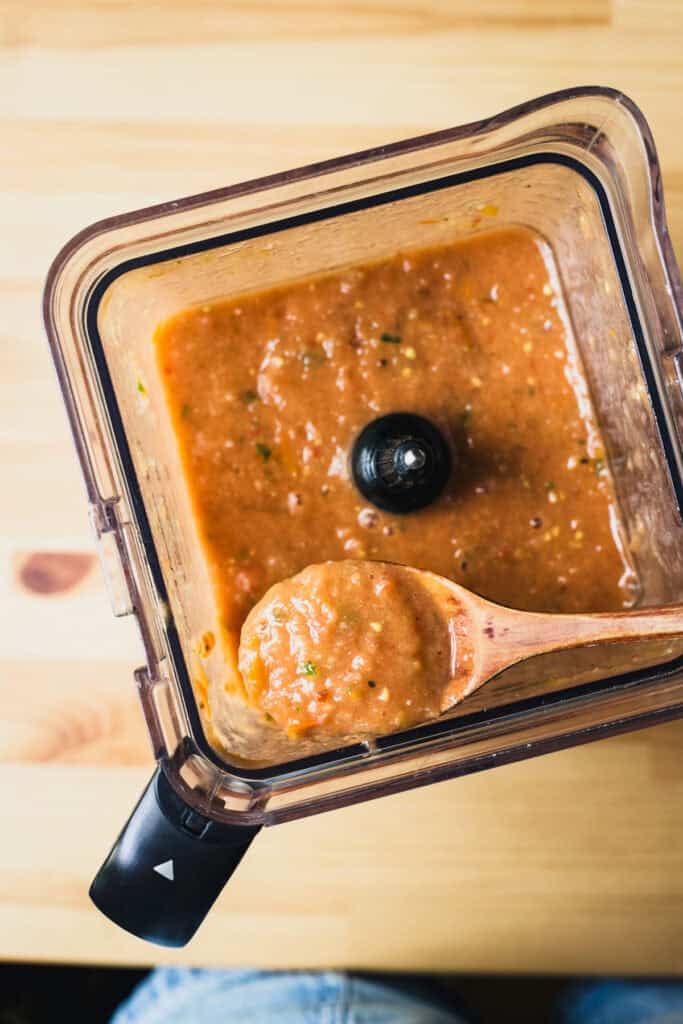 Gazpacho in a blender with a spoon scooping some up.