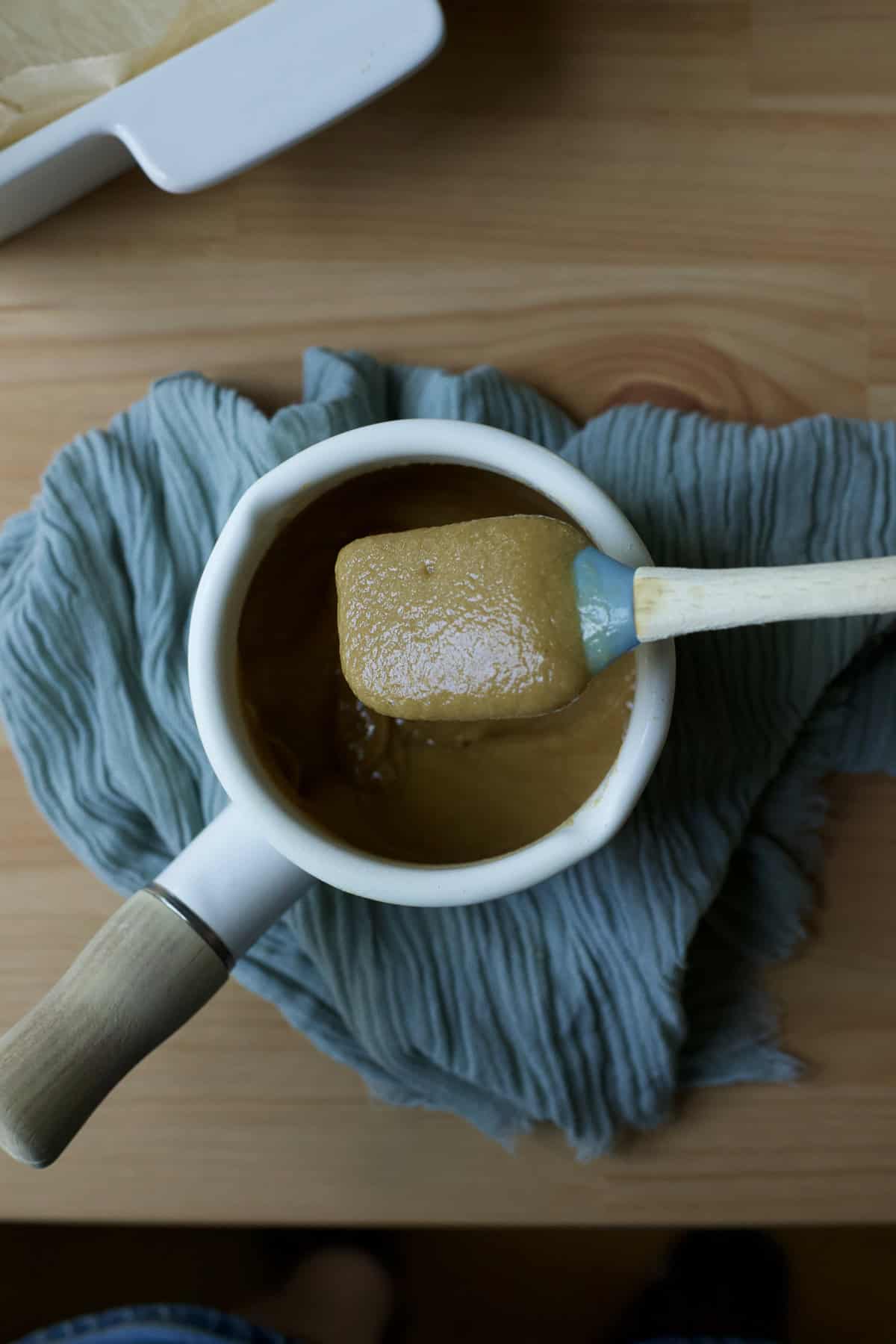 Heating tahini, honey, and vanilla extract together in a small saucepan.