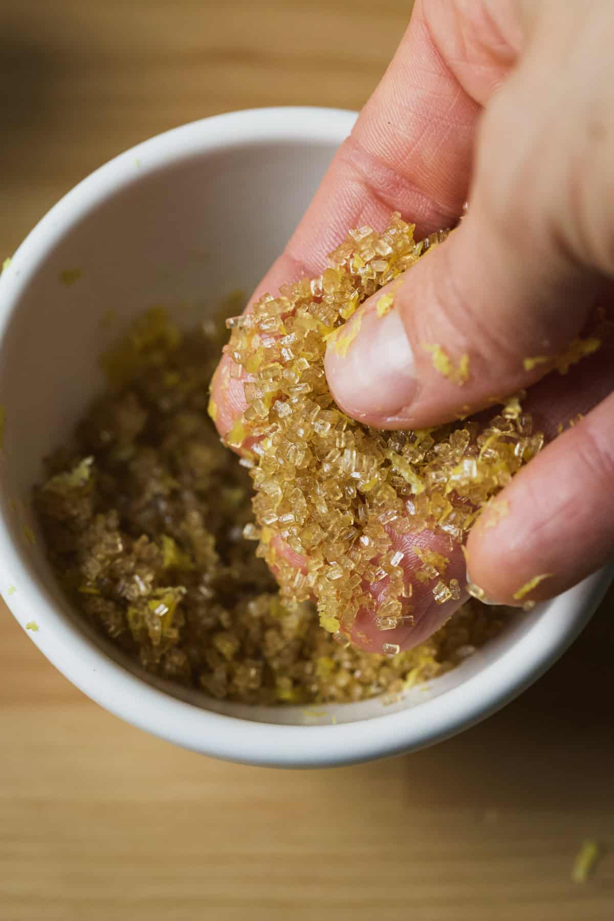 Rubbing turbinado sugar and lemons zest together between fingers to make homemade lemon sugar.