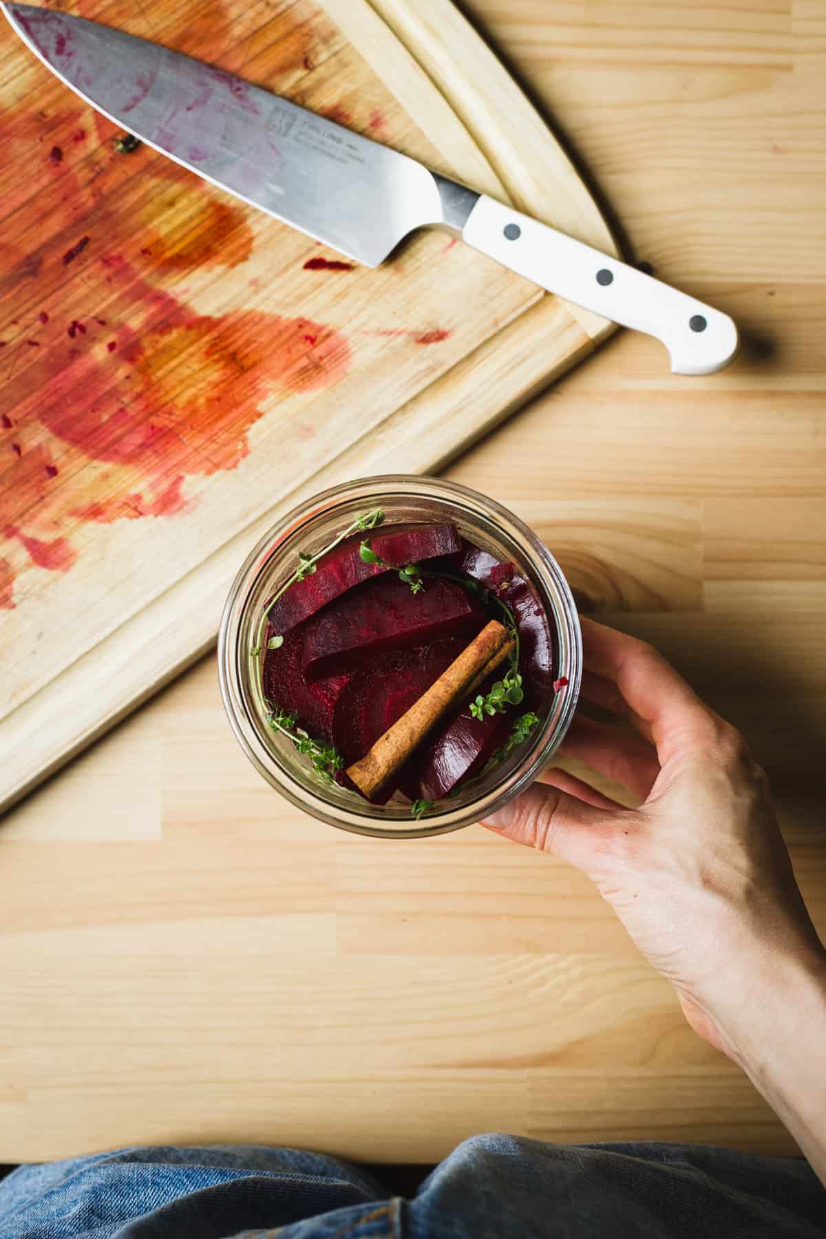 Jar of sliced beets, cinnamon sticks, star anise, and fresh thyme for making pickled beets.