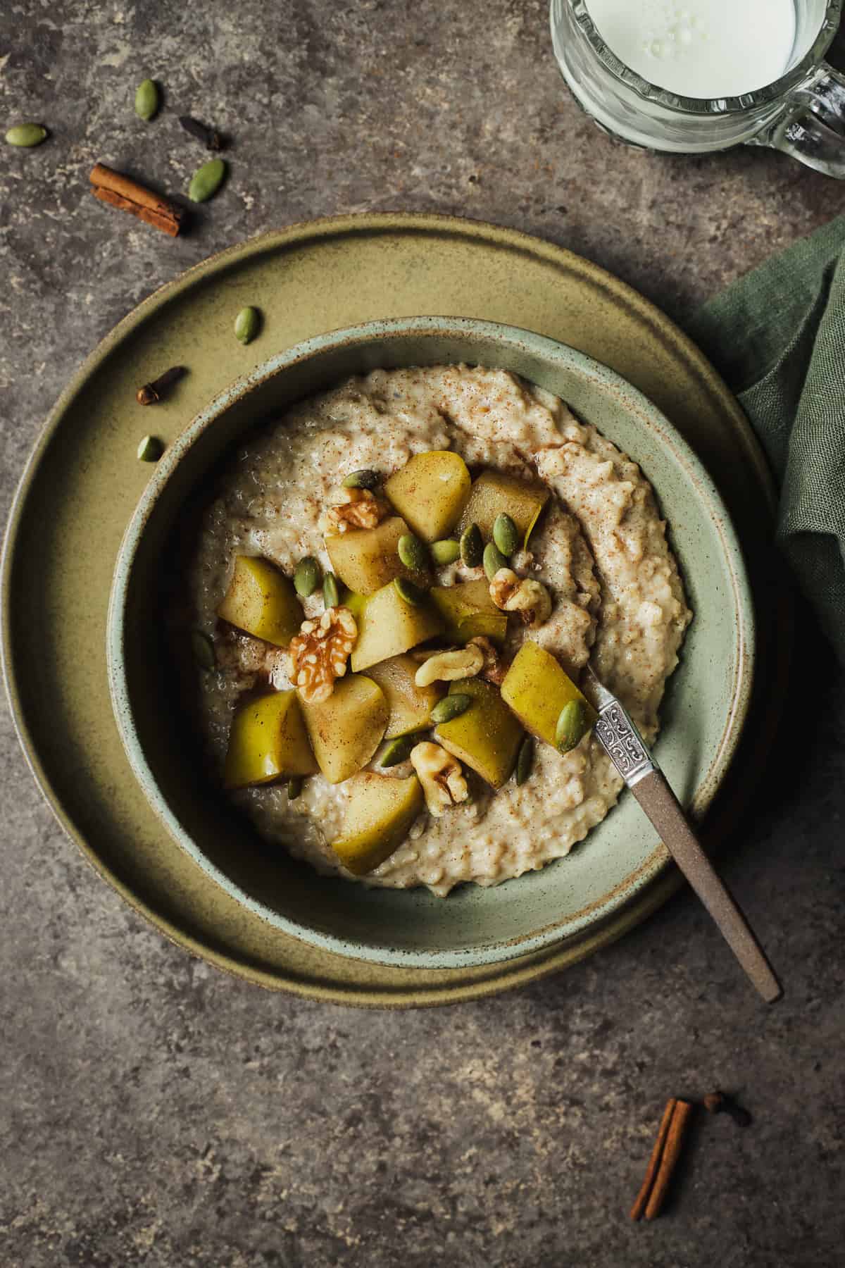 Chai oatmeal in a bowl with stewed apples, walnuts, and pepitas on top.