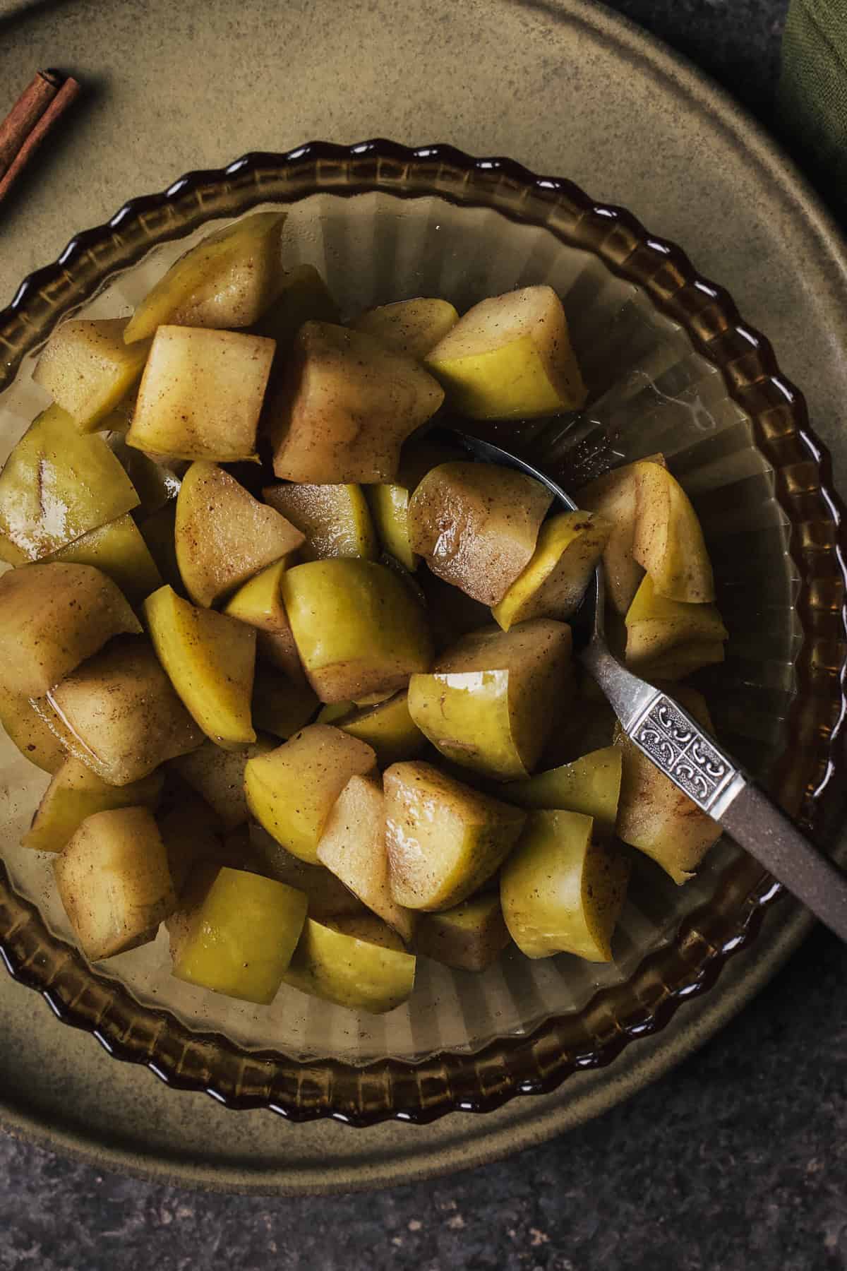 Cinnamon stewed apples in a bowl with spoon.